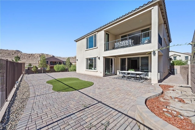 12705 Coastline Shadow St, Las Vegas, NV 89141 - rear view of house featuring a balcony, stucco siding, a fenced backyard, a patio, and a tiled roof