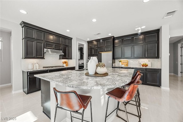 12705 Coastline Shadow St, Las Vegas, NV 89141 - kitchen featuring baseboards, stainless steel gas stovetop, backsplash, light stone countertops, and recessed lighting