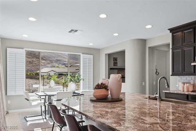 12705 Coastline Shadow St, Las Vegas, NV 89141 - kitchen with a sink, light stone countertops, recessed lighting, a kitchen breakfast bar, and dark brown cabinets