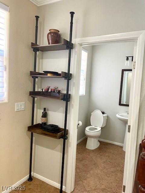 bathroom featuring baseboards, tile patterned floors, ornamental molding, and toilet