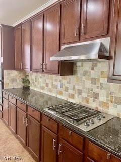 kitchen featuring backsplash, dark stone countertops, stainless steel gas cooktop, and under cabinet range hood