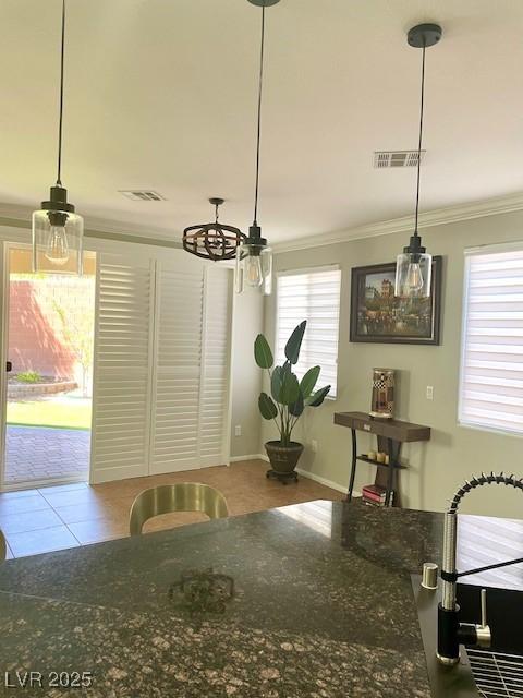 tiled dining room featuring visible vents, ornamental molding, a chandelier, and a healthy amount of sunlight