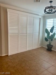 interior space with an inviting chandelier, baseboards, ornamental molding, and visible vents