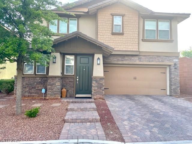 craftsman-style house with an attached garage, stucco siding, and stone siding