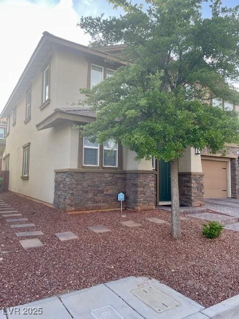 view of front of house with a garage, stucco siding, and stone siding