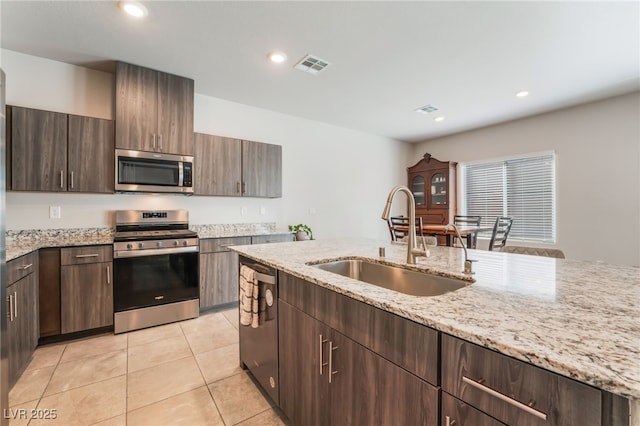 kitchen with visible vents, light tile patterned flooring, light stone counters, a sink, and stainless steel appliances