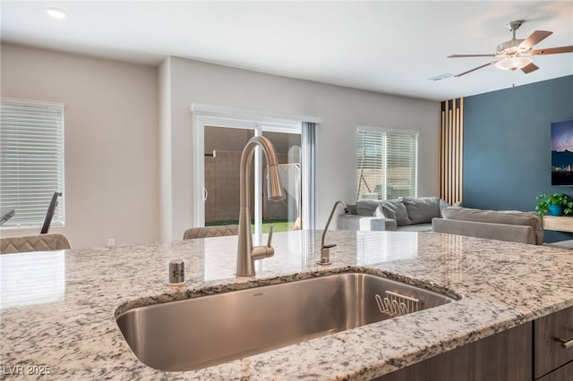 interior details featuring a sink, ceiling fan, and light stone countertops