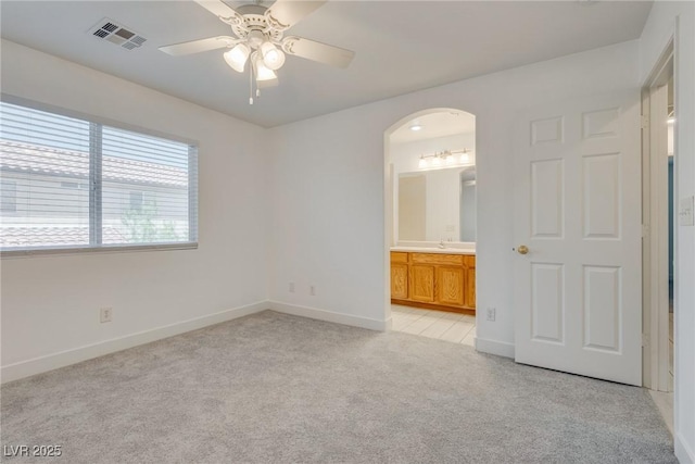 8824 Charm Canyon Ave, Las Vegas, NV 89178 - spare room featuring visible vents, baseboards, ceiling fan, light colored carpet, and arched walkways