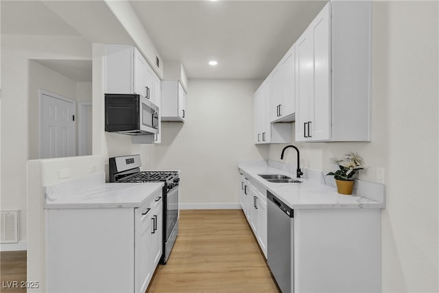 kitchen featuring visible vents, baseboards, light stone counters, a sink, and appliances with stainless steel finishes