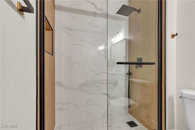 bathroom with toilet and a marble finish shower