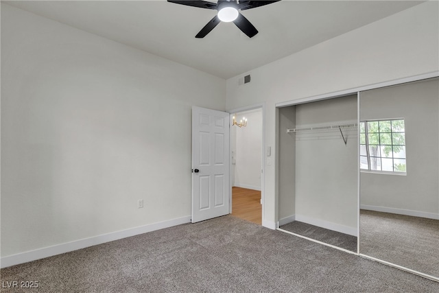 unfurnished bedroom featuring visible vents, a closet, baseboards, carpet, and ceiling fan with notable chandelier