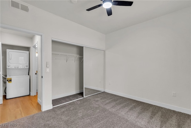 unfurnished bedroom with carpet, baseboards, stacked washer / drying machine, and visible vents