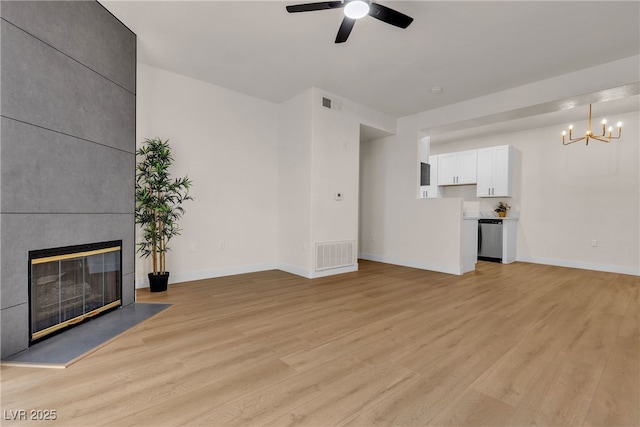 unfurnished living room with light wood-style floors, ceiling fan with notable chandelier, and visible vents