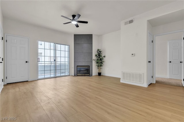unfurnished living room with ceiling fan, a fireplace, light wood-style flooring, and visible vents