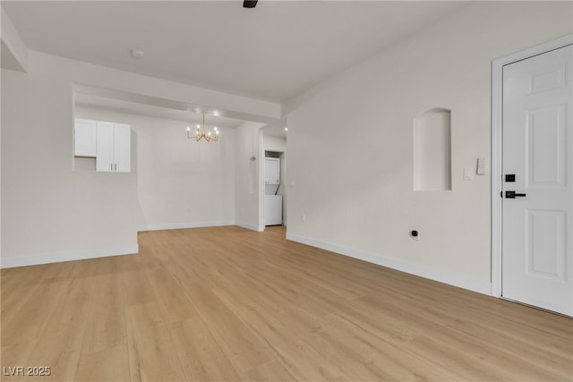 spare room with baseboards, light wood-style flooring, and a notable chandelier