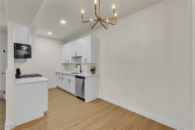 kitchen featuring stainless steel dishwasher, baseboards, a sink, and light wood-type flooring