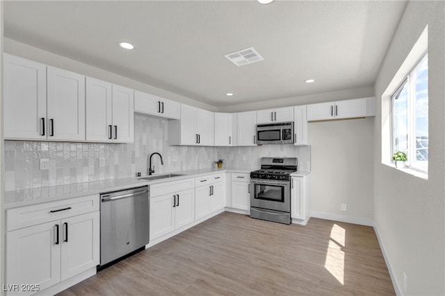 kitchen featuring a sink, decorative backsplash, stainless steel appliances, and visible vents