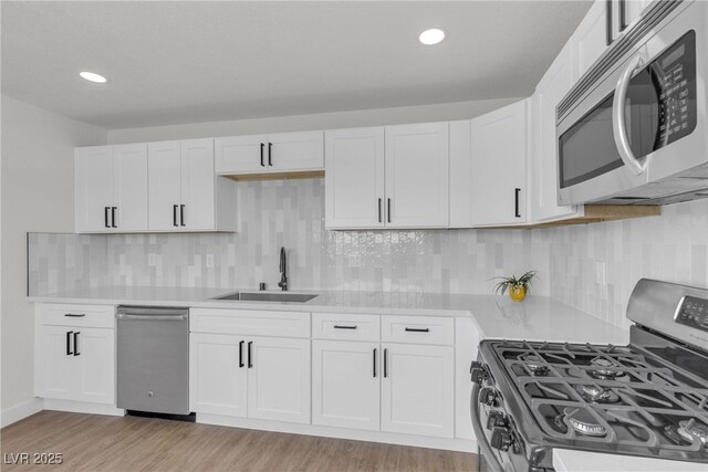 1424 Balzar Ave, Las Vegas, NV 89106 - kitchen featuring appliances with stainless steel finishes, a sink, light countertops, light wood-type flooring, and white cabinets