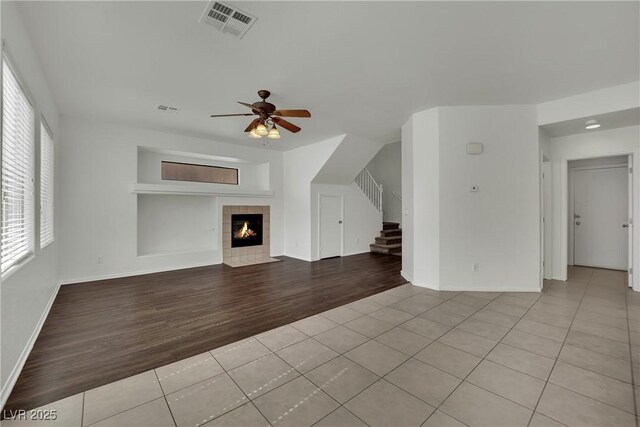 6525 Bismark Hills St, North Las Vegas, NV 89084 - unfurnished living room featuring light tile patterned floors, a ceiling fan, stairway, a tiled fireplace, and baseboards