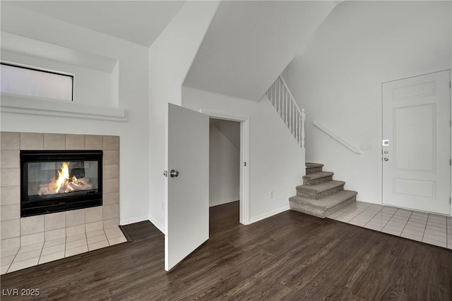 6525 Bismark Hills St, North Las Vegas, NV 89084 - unfurnished living room with wood finished floors, stairway, a fireplace, baseboards, and high vaulted ceiling