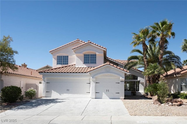 mediterranean / spanish home featuring concrete driveway, an attached garage, a tile roof, and stucco siding