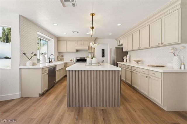 kitchen with appliances with stainless steel finishes, a sink, decorative backsplash, under cabinet range hood, and visible vents