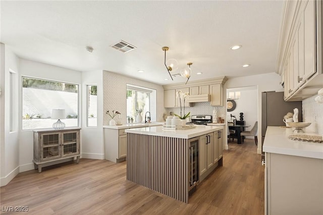 kitchen featuring stainless steel range, light wood-style floors, light countertops, under cabinet range hood, and visible vents