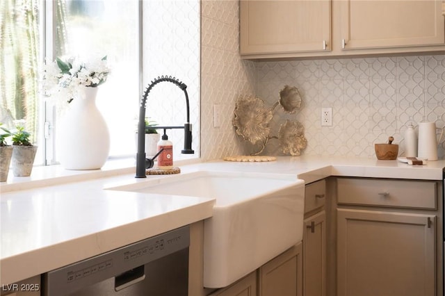 kitchen featuring a sink, backsplash, dishwasher, and light countertops