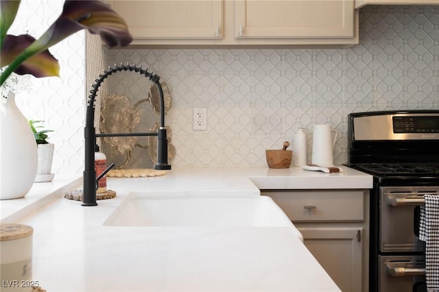 interior space featuring light countertops, stainless steel range, backsplash, and a sink