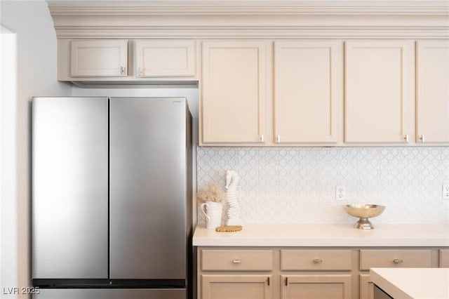 kitchen featuring freestanding refrigerator, tasteful backsplash, cream cabinetry, and light countertops