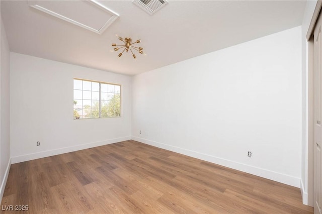 empty room featuring baseboards, attic access, light wood-type flooring, and visible vents