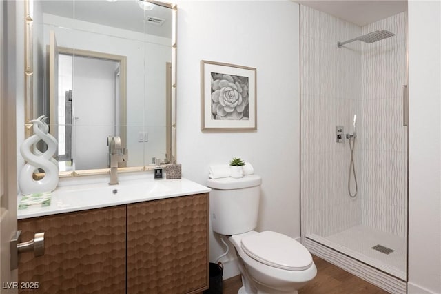 full bathroom featuring visible vents, vanity, wood finished floors, toilet, and tiled shower