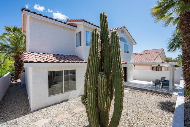 back of house featuring a pergola, a tile roof, stucco siding, a patio, and fence private yard