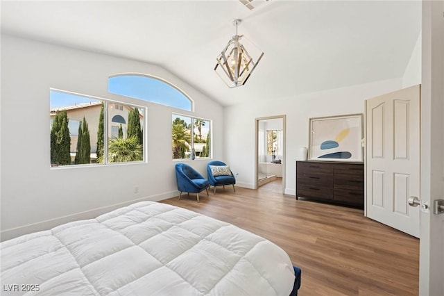bedroom with an inviting chandelier, ensuite bath, baseboards, wood finished floors, and vaulted ceiling