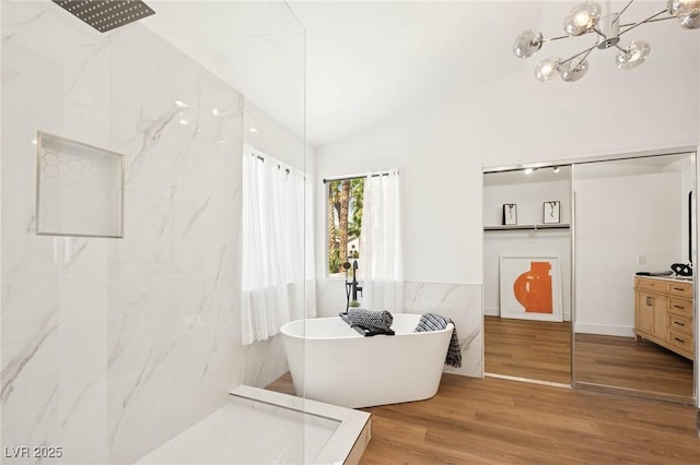 full bath with vanity, a freestanding tub, wood finished floors, a chandelier, and a marble finish shower