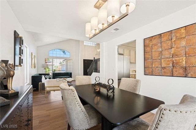 dining room featuring visible vents, lofted ceiling, wood finished floors, and stairway