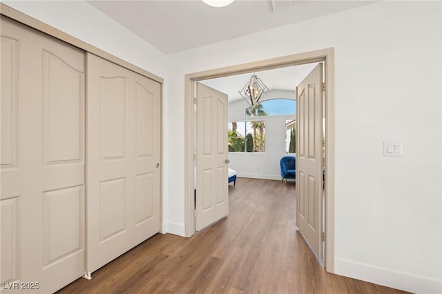 hall featuring baseboards, a notable chandelier, visible vents, and light wood-style floors