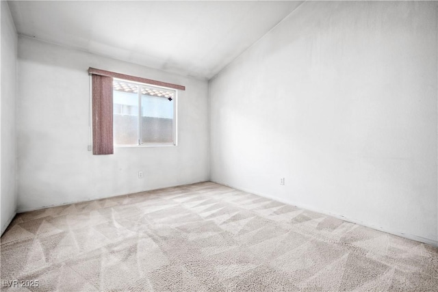 carpeted spare room featuring vaulted ceiling