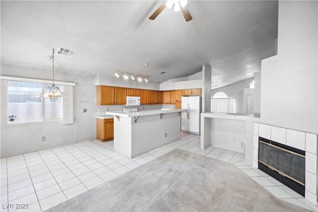 kitchen featuring light tile patterned flooring, white microwave, light countertops, a kitchen bar, and refrigerator with ice dispenser