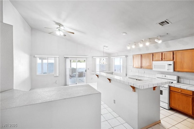 kitchen with ceiling fan, visible vents, vaulted ceiling, tile counters, and white appliances