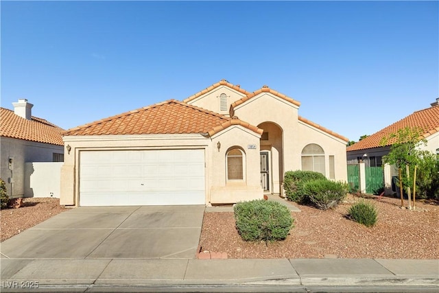 mediterranean / spanish house with a garage, stucco siding, driveway, and a tile roof