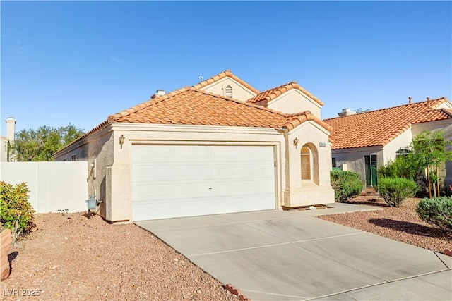 mediterranean / spanish home with fence, an attached garage, a tile roof, stucco siding, and concrete driveway