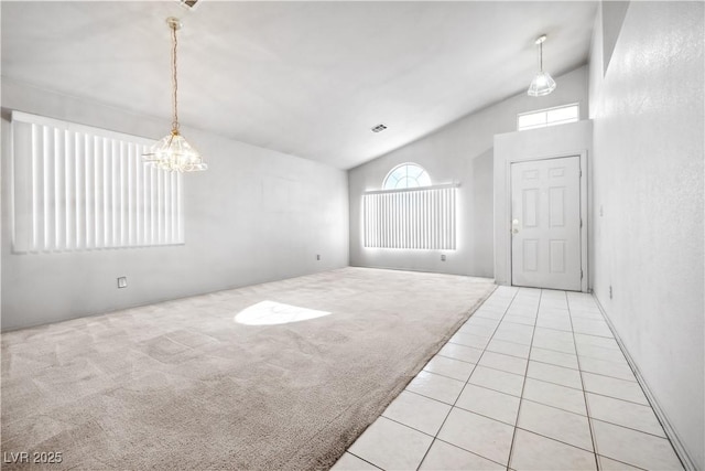 tiled foyer entrance with visible vents, carpet, lofted ceiling, and a chandelier