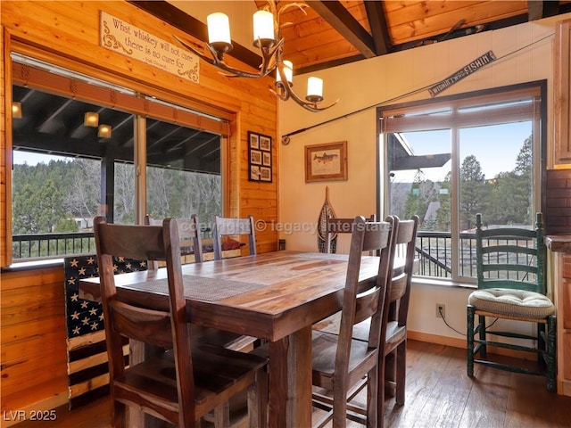 dining room featuring wooden walls, a notable chandelier, hardwood / wood-style floors, and a healthy amount of sunlight