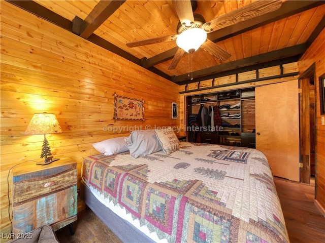 bedroom featuring beamed ceiling, wood walls, wooden ceiling, and a closet