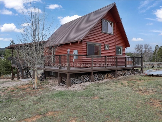 back of property featuring a lawn, log veneer siding, metal roof, and a deck