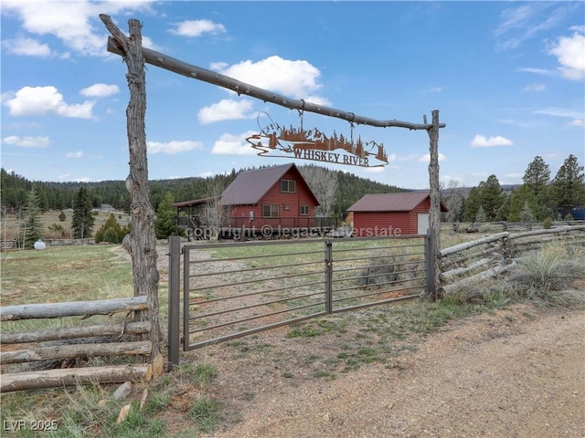 exterior space featuring a forest view, a rural view, fence, and an outdoor structure