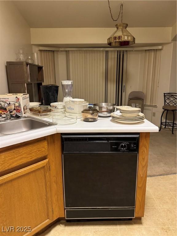 kitchen featuring dishwasher, a sink, light countertops, and brown cabinets