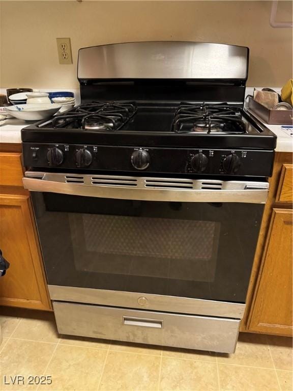kitchen view of stainless steel range with gas cooktop, brown cabinetry, and light countertops