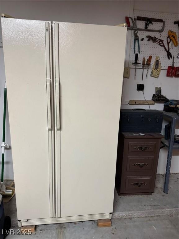 detailed view of freestanding refrigerator and unfinished concrete floors